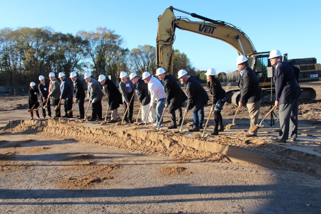 Construction workers and officials breaking ground with shovels at new project site.